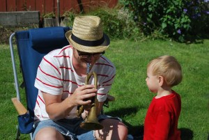 Blake teaches Henry how to blow a horn.